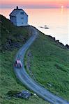 Remote house at the edge of shore at sunset