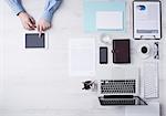 Businessman working at office desk and using a digital touch screen tablet hands detail, computer and objects on the right, top view