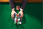 Poker player betting all in and holding a lot of chips stacks, hands close up, top view