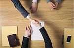 Business people at office desk handshaking after signing an agreement, hands top view, unrecognizable people