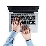 Businessman working at computer and typing on a laptop keyboard, top view, hands close up