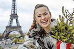 The Party Season in Paris. Portrait of smiling trendy fashion-monger with Christmas tree in fur coat in Paris, France taking selfie