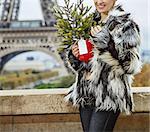 The Party Season in Paris. Portrait of happy trendy fashion-monger with Christmas tree in fur coat in Paris, France looking into the distance