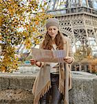 Autumn getaways in Paris. young tourist woman on embankment near Eiffel tower in Paris, France looking at the map