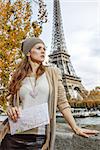 Autumn getaways in Paris. young tourist woman on embankment in Paris, France with map looking into the distance