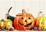 Halloween holiday still life happy scary pumpkin jack-o-lantern with dry leaf and acorns on wooden board close-up