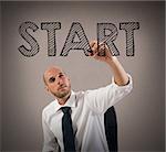 Businessman writing the word start with a pen