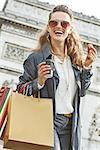 Stylish autumn in Paris. smiling trendy woman in sunglasses with shopping bags in Paris, France having coffee and macaroon