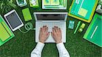 Businessman using a laptop and networking on the grass; green business, sustainability and communication concept