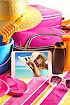 Tablet showing vacations pictures with towel, sunglasses, sun creams and beach accessories.