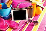 Empty touch screen tablet with colorful beach towel, sunglasses, sun creams and beach accessories.