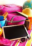 Empty blackboard with summer holidays background, including sunglasses, sun cream and bag.