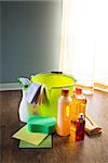 Wood cleaners and detergents on floor with bucket, gloves, cloth and sponges.