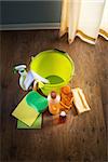 Wood cleaners and detergents on floor with bucket, gloves, cloth and sponges.