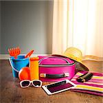 Summer vacations packing with colorful accessories and digital tablet.