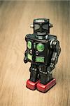 Vintage funny tin toy robot on hardwood floor looking at camera.