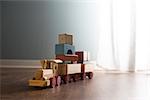 Vintage wooden toy train next to a window on hardwood floor.