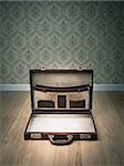 Open vintage leather briefcase on hardwood floor, retro wallpaper on background.