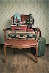 Family holiday packing with vintage suitcases and toys on elegant red velvet armchair.