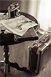 Old maps and book on a table with retro camera and suitcase on background.