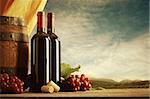 Red wine bottles with barrel and grapes, vineyard on background