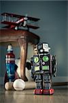 Funny tin toy robot on hardwood floor with vintage toys on background.