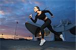 Concept: healthy lifestyle, sport. Attractive happy girl fitness trainer run outdoor workout at modern downtown urban area during sunset.