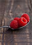 Raspberries on old spoon on grunge wooden board. Natural healthy food. Still life photography