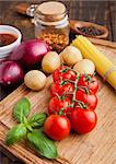 Fresh organic tomatoes with vegetables on wooden board. Potatoes,onion,sause.spices,basil