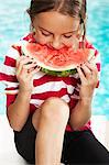 Girl eating watermelon at poolside