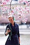 Young woman with mp3 player near cherry blossom trees
