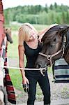 Young woman brushing horse