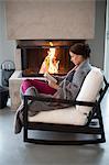 Young woman sitting in front of fireplace and reading