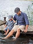 Man with son sitting on jetty at lake