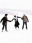 Three people skating, holding hands.