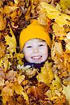 Portrait of happy girl surrounded by autumn leaves