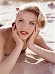 Portrait of young woman with retro hairstyle lying on sand