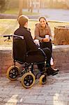 Young woman and man on wheelchair having coffee break