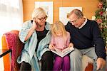 Grandparents reading book with granddaughter