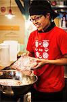 The ramen noodle shop. A chef preparing a huge metal bowl of broth with meat ingredients.