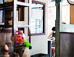 The ramen noodle shop. A woman sitting in a cafe, view through a door.