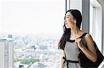 A business woman by a window with a view over the city,