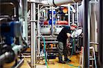 Man working in a brewery adjusting and checking the machinery which transfers the brewed beer around the processing plant.