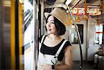Young woman wearing a hat traveling on a train.