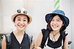 Portrait of two smiling young women wearing hats.