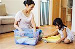 Family home. A woman and her daughter folding clean laundry.