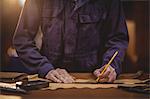 Shoemaker cutting a piece of leather in workshop