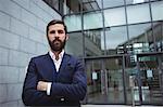 Portrait of businessman standing with arms crossed outside office