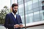 Businessman using mobile phone outside office