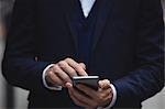 Mid section of businessman using mobile phone